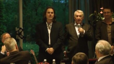 Marcel Harmsen in conversation with an older man in front of a standing audience